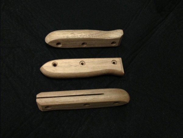 Three custom walnut knife handles with slotted sides and pre-drilled holes for secure blade attachment.